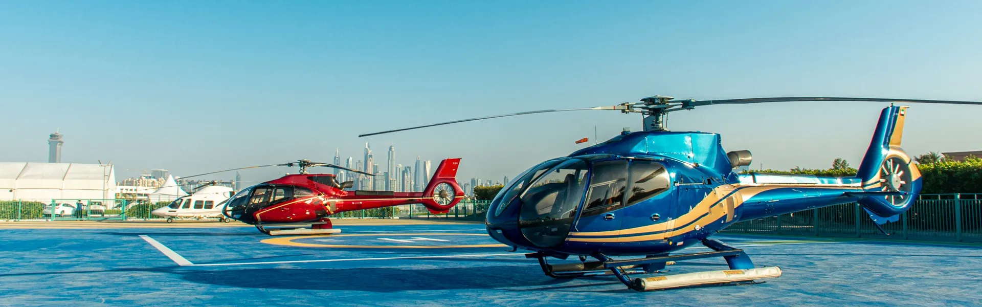 Two Helicopter Ride and Tours Dubai helicopters on a Dubai helipad with the Marina skyline behind